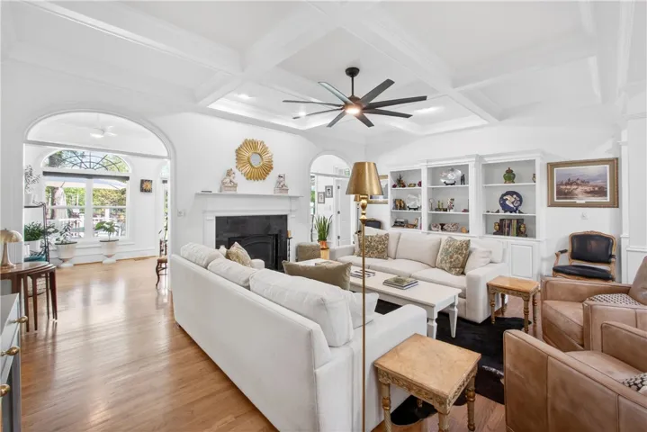 This bright living area features built-in shelving, a cozy fireplace, and rich hardwood floors.