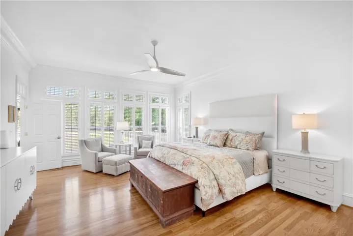 This airy bedroom features hardwood floors and ample natural light, creating a bright and inviting space.