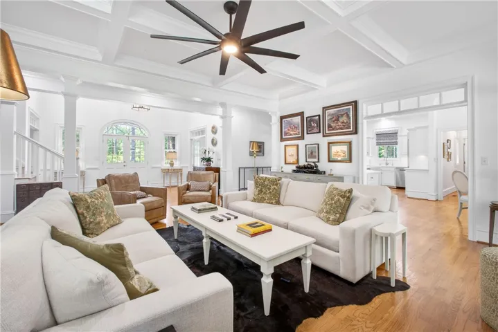 This bright living space features hardwood floors, a coffered ceiling, and an inviting open floor plan.