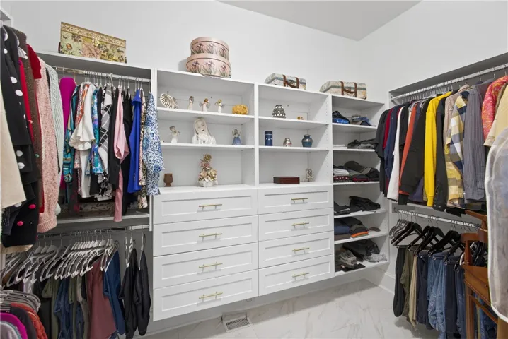 This spacious walk-in closet offers extensive storage solutions with elegant built-in shelving and drawers.