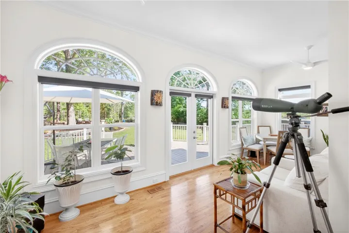 This bright living space features hardwood floors, tall arched windows, and a ceiling fan, creating an inviting atmosphere.