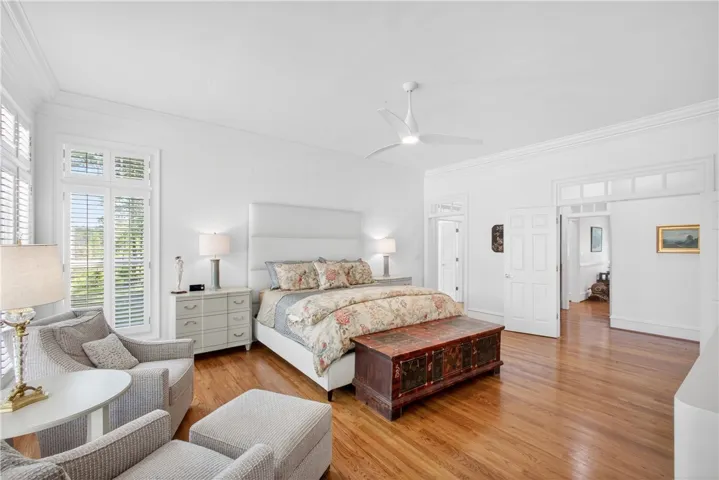 This spacious primary bedroom features rich hardwood flooring and elegant crown molding.