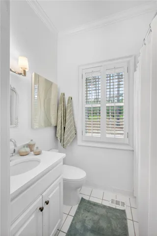 This bright bathroom features crown molding and a window offering natural light.