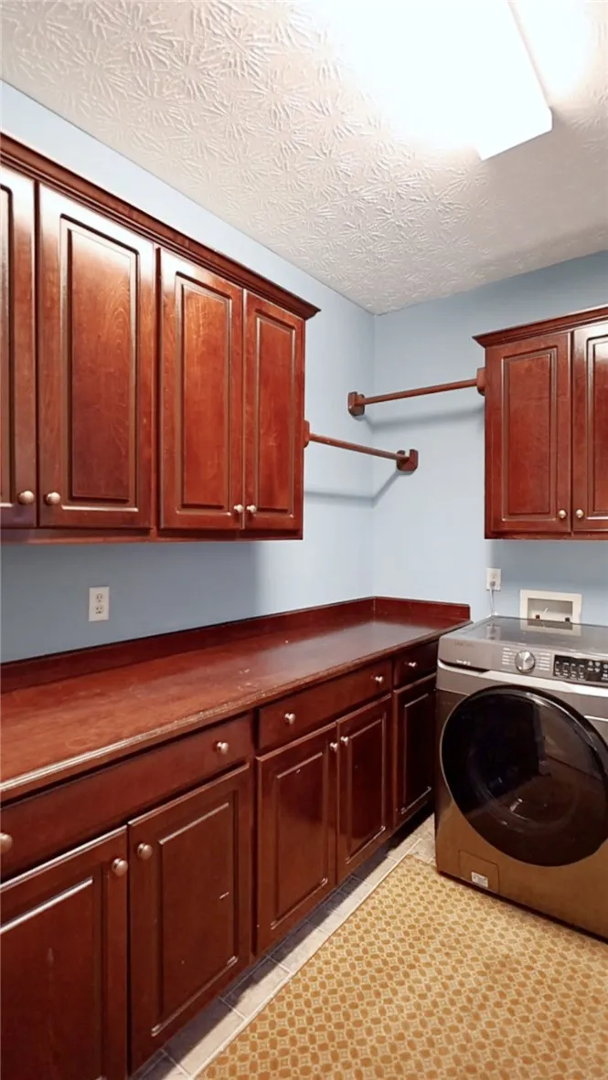 Functional laundry space featuring ample cabinetry and a convenient drying area.