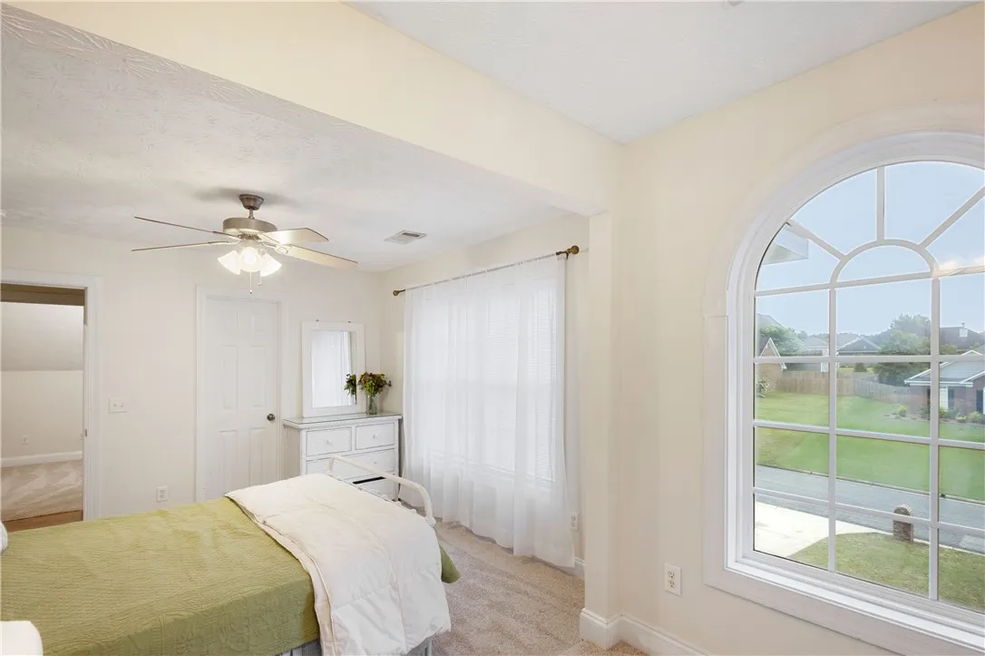 This serene bedroom offers ample light and comfortable living, with a view of the peaceful outdoors.
