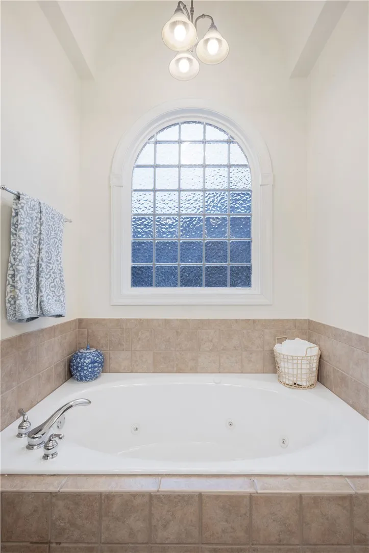Relax in this inviting tub, featuring a beautiful arch window with textured glass.