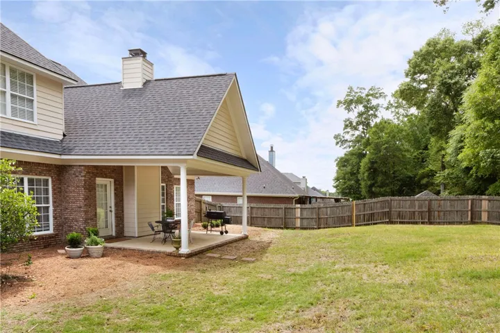 This outdoor space features a covered patio and a spacious backyard, ideal for relaxation and entertaining.