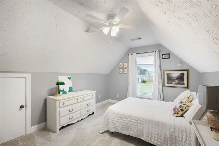 This cozy bedroom features a sloped ceiling, providing a unique and comfortable living space.