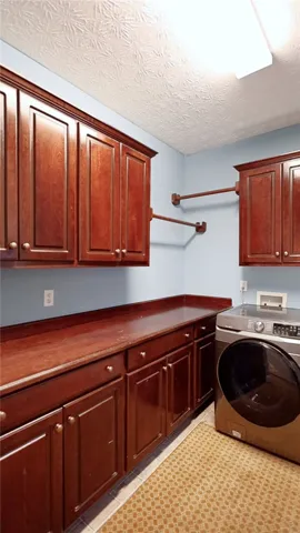 Functional laundry space featuring ample cabinetry and a convenient drying area.