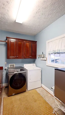 Functional laundry space featuring convenient cabinetry and durable flooring for daily tasks.