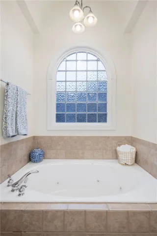Relax in this inviting tub, featuring a beautiful arch window with textured glass.