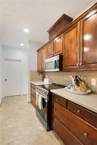 This kitchen offers warm wood cabinetry, modern appliances, and practical tiled flooring.