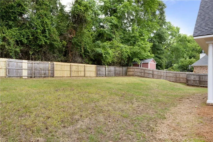 This spacious yard offers privacy and a convenient storage shed, perfect for outdoor living.