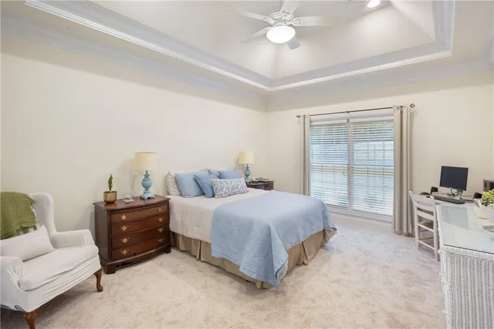 This tranquil bedroom features carpet flooring and elegant tray ceilings, creating a serene personal retreat.