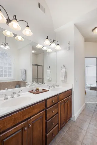 This bathroom features a double vanity and sleek tiled flooring.