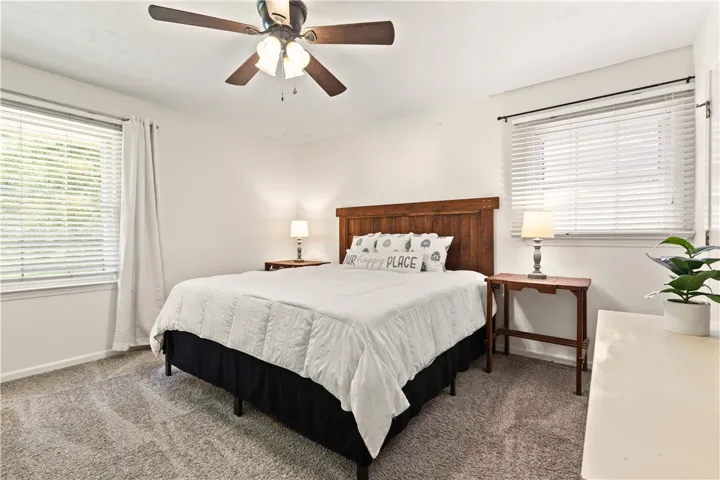 This cozy bedroom offers a serene retreat with soft carpeting and natural light filtering through the windows.