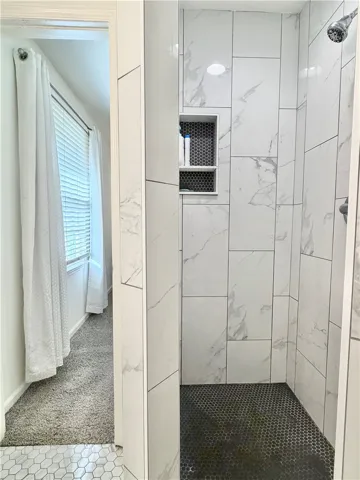 This sleek bathroom features a contemporary shower with elegant tiling.