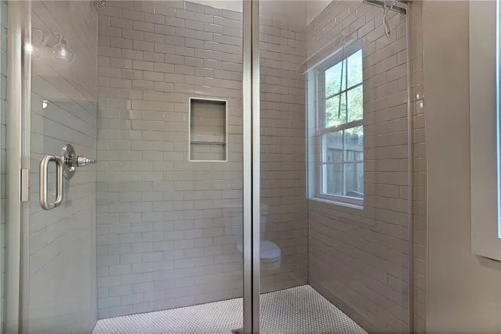This bathroom features a tiled shower with a window, creating a refreshing bathing experience.