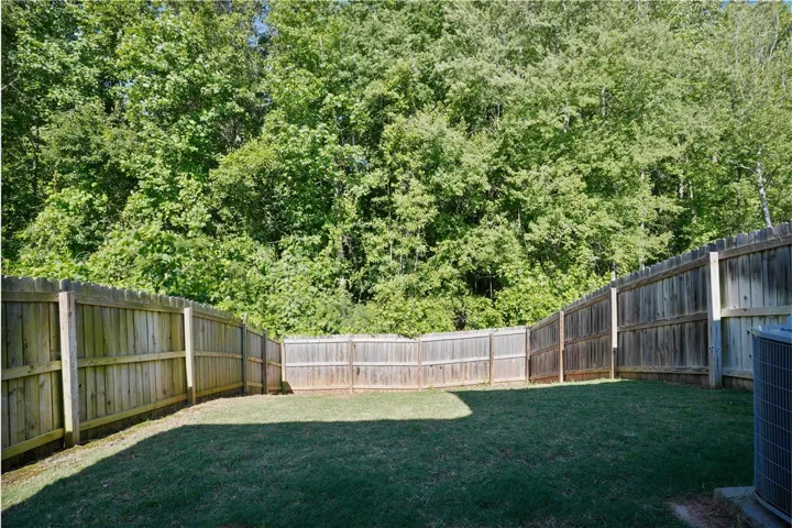 This private yard offers serene views of lush, mature trees, perfect for outdoor enjoyment.
