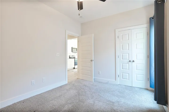 This spacious bedroom offers comfortable carpeting and a convenient view into the adjacent kitchen.