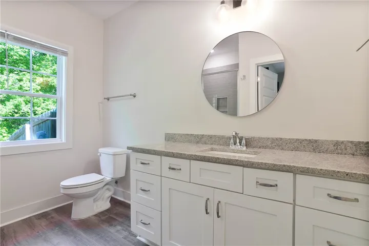 This bright bathroom features a spacious vanity and a window with a lush outdoor view.