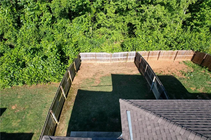 This spacious private yard offers a tranquil retreat surrounded by lush greenery and a sturdy fence.