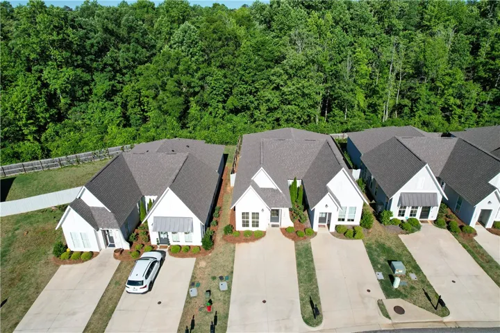 These charming homes feature ample green spaces and a serene backdrop of mature trees.