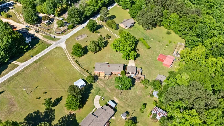 This expansive aerial view showcases a verdant property with multiple structures nestled within lush surroundings.