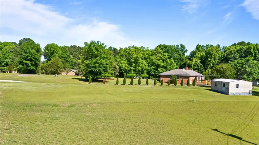 Expansive green grounds surround a welcoming brick residence with an additional storage shed.