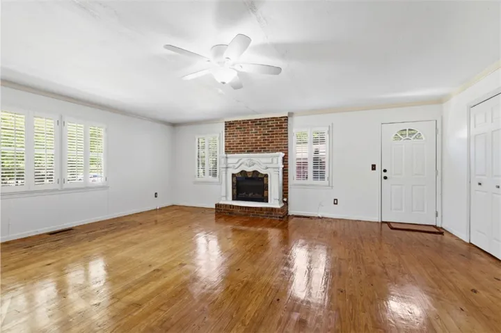 Bright and airy living area with a brick gas fireplace and original hardwood floors.