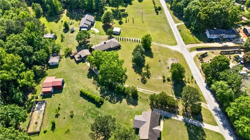 An aerial view showcases a verdant rural landscape with residential properties and expansive green spaces.