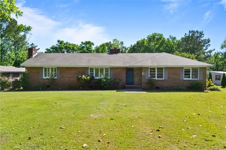 Brick ranch home featuring a classic design and expansive front yard.