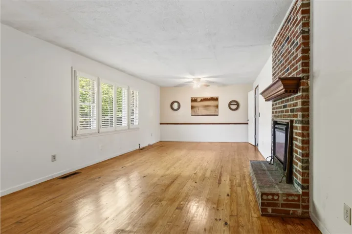This bright living space features original wood flooring and a brick gas fireplace, creating a warm and inviting atmosphere.
