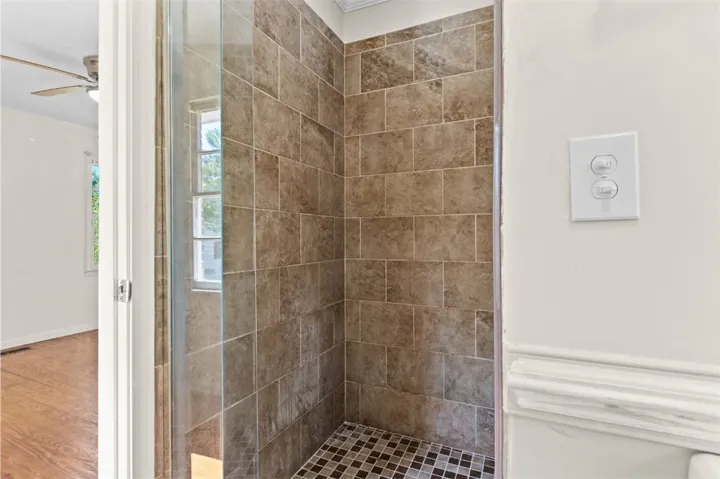 This updated bathroom features a sleek, tiled shower with a glass door.