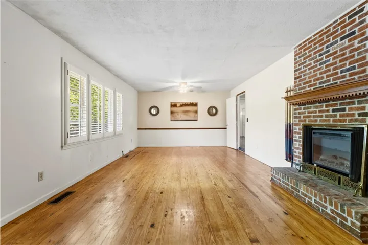 This bright living space features original wood flooring and a classic brick fireplace, creating a warm ambiance.