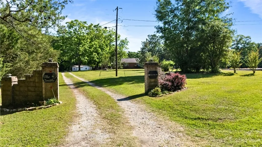 A long gravel driveway leads to a secluded home nestled among mature trees.