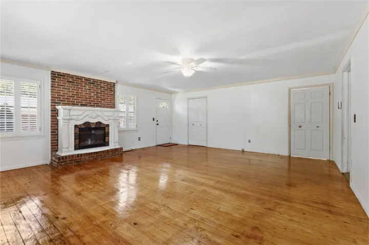 This living area features a brick fireplace, original hardwood floors, and a ceiling fan.