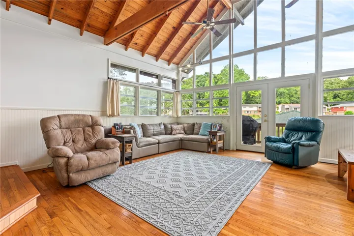 Vast window walls and a soaring wood-beamed ceiling define this airy living space.