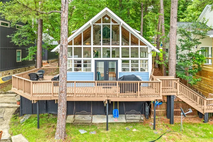 A stunning A-frame home showcases a towering wall of windows and an expansive outdoor deck.