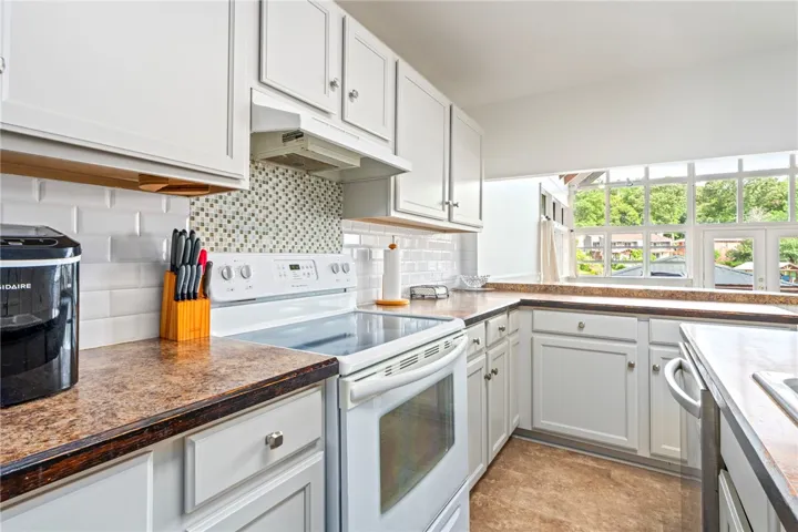 A well-equipped kitchen features ample counter space, bright cabinetry, and expansive windows offering a scenic outdoor outlook.