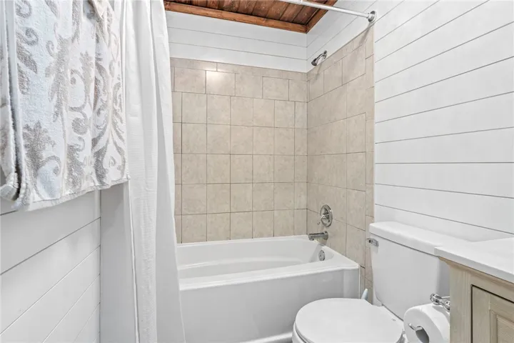 A pristine bathroom features a classic bathtub with tiled surround and crisp shiplap walls.