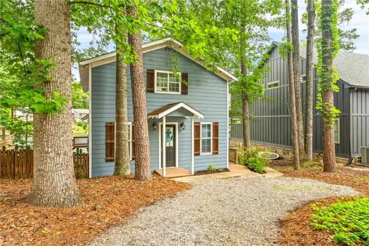 Embrace woodland tranquility in this charming abode, featuring a welcoming gravel driveway and natural landscaping.