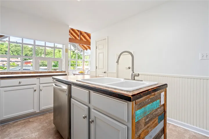 A rustic-chic kitchen island with a double sink and stainless steel appliances, bathed in natural light.