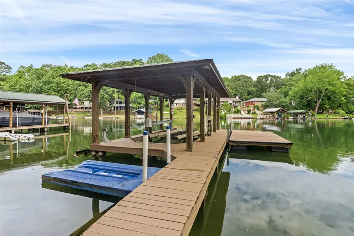 A spacious covered boat dock and additional floating dock extend over placid waters, offering direct lake access.