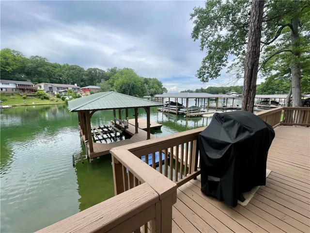 A spacious wooden deck extends over the shimmering lake, offering direct access to the water and multiple boat slips.