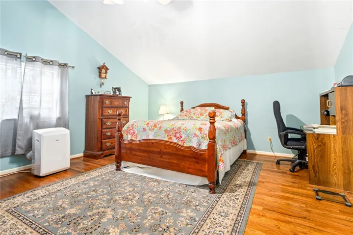 Hardwood floors and a vaulted ceiling elevate this comfortable and well-lit sleeping area.