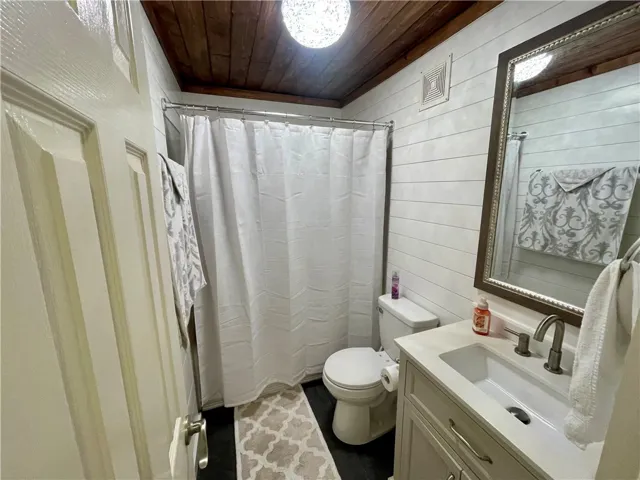 A well-appointed bathroom features shiplap walls, a wooden ceiling, and a clean white vanity with a sleek faucet.