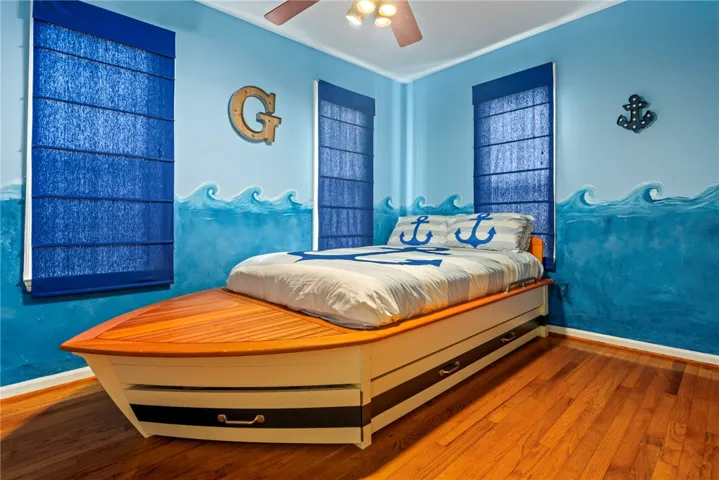 Hardwood floors and vivid blue walls with wave accents create a playful, nautical-themed sleeping space.