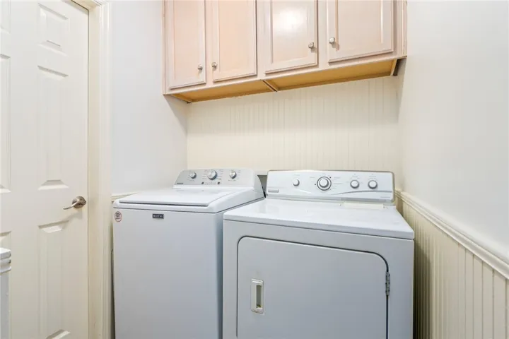 Functional laundry space featuring modern appliances and convenient overhead storage.