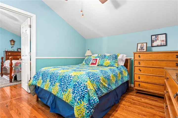 Hardwood floors and a pitched ceiling define this airy, well-lit bedroom.
